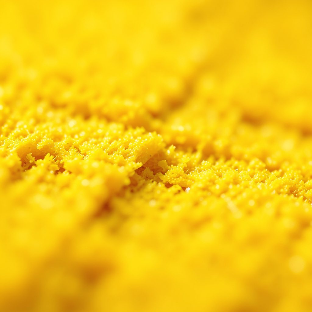 Close-up tekstur permukaan gelap berpola halus dengan sentuhan kuning keemasan, suasana tenang dan elegan